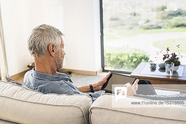 Älterer Mann benutzt Tablette auf Couch zu Hause