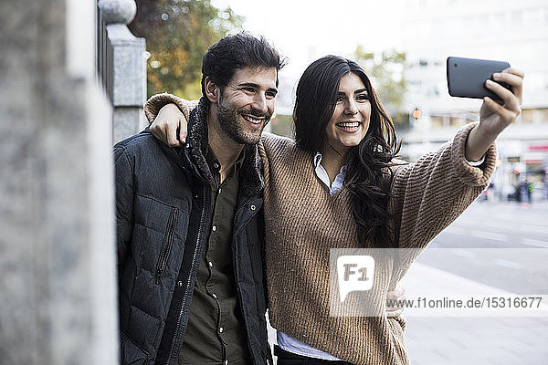 Porträt eines glücklichen Paares  das sich mit dem Handy selbstständig macht