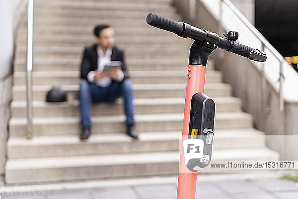 Close-up of e-scooter with businessman in background