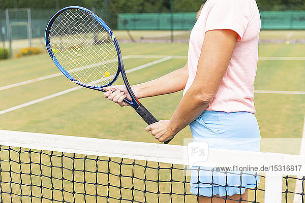 Tennisspielerin hält den Schläger auf dem Rasenplatz