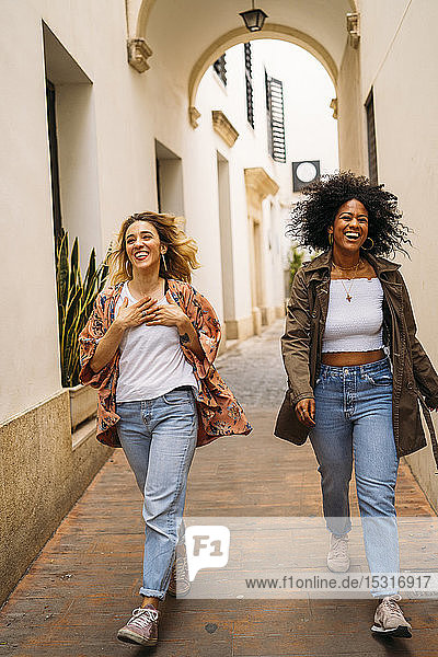 Multikulturell lachende Frauen gehen in der Stadt spazieren