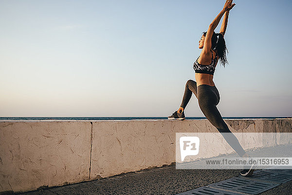Young sports woman stretching her leg on a pier