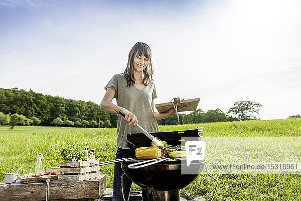 Lächelnde Frau bei der Zubereitung von Gemüse auf dem Barbecue-Grill