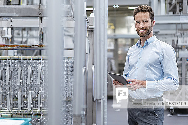 Portrait of smiling businessman with tablet in a modern factory
