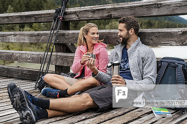 Young couple having a break on a wooden bridge during a hiking trip  Vorderriss  Bavaria  Germany