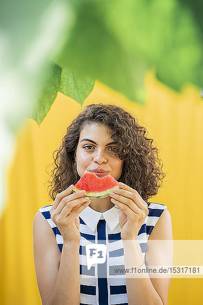 Porträt einer Frau  die eine Wassermelone isst  gelber Hintergrund