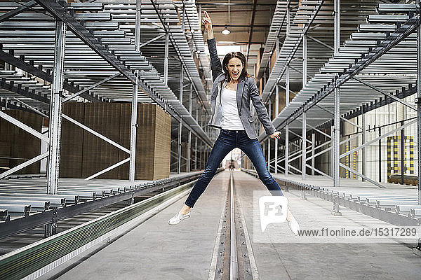 Aufgeregte Geschäftsfrau springt in Fabrik