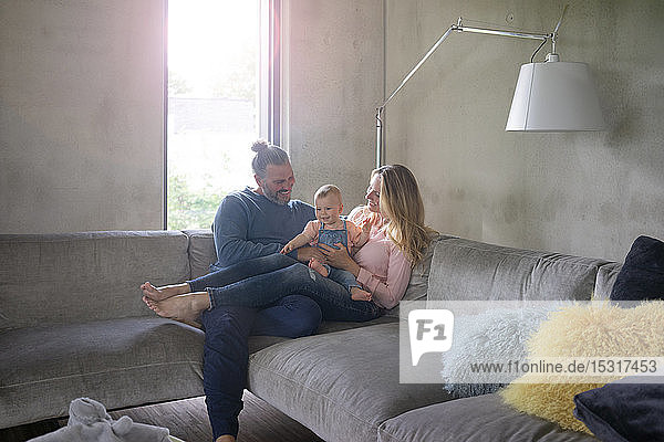 Glückliche dreiköpfige Familie sitzt zu Hause auf der Couch
