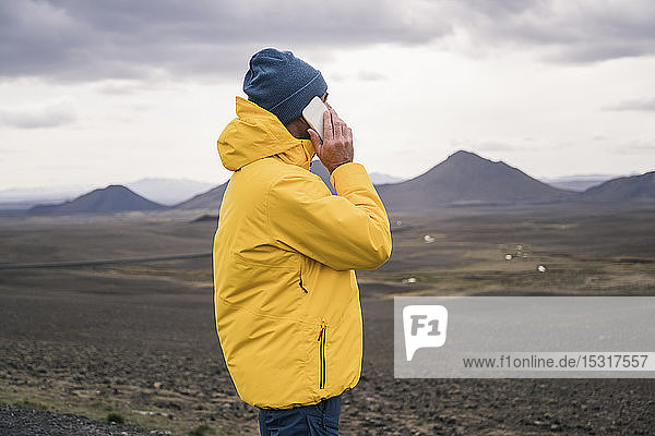 Reifer Mann spricht auf seinem Smartphone im isländischen Hochland