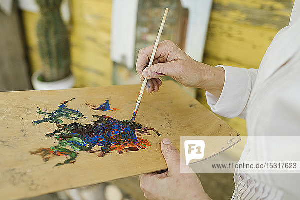 Hände einer Künstlerin beim Mischen von Farben