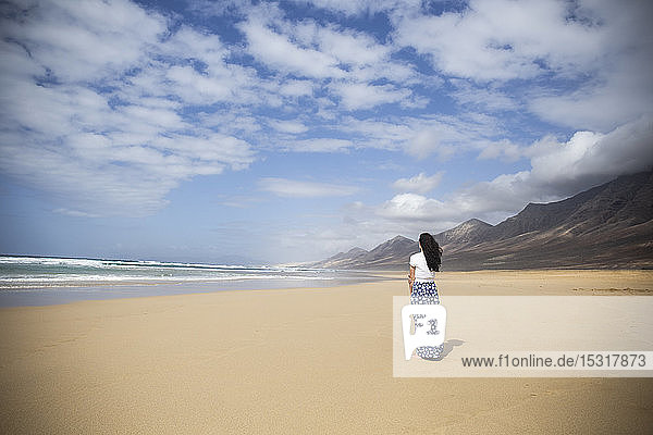 Rückenansicht einer am Strand stehenden Frau mit Blick auf das Meer  Fuerteventura  Spanien