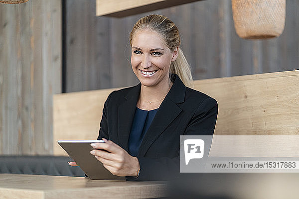 Porträt einer lächelnden blonden Geschäftsfrau mit digitalem Tablet in einem Café
