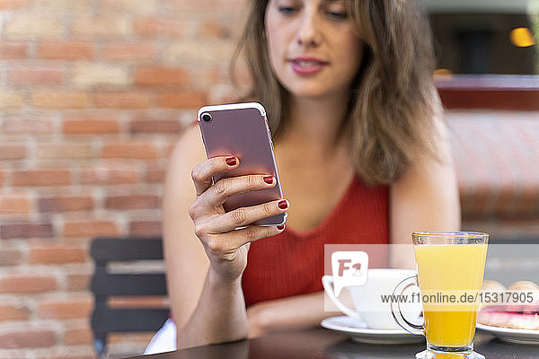 Hand einer jungen Frau im Straßencafé mit einem Smartphone in der Hand  Nahaufnahme