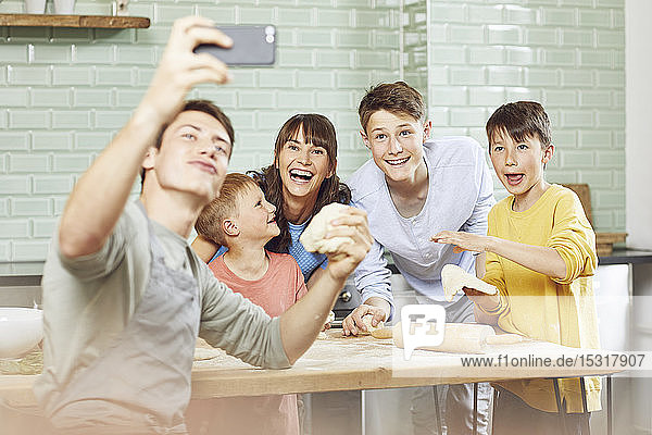 Sone taking pictures of his mother and brothers  preparing pizza at home