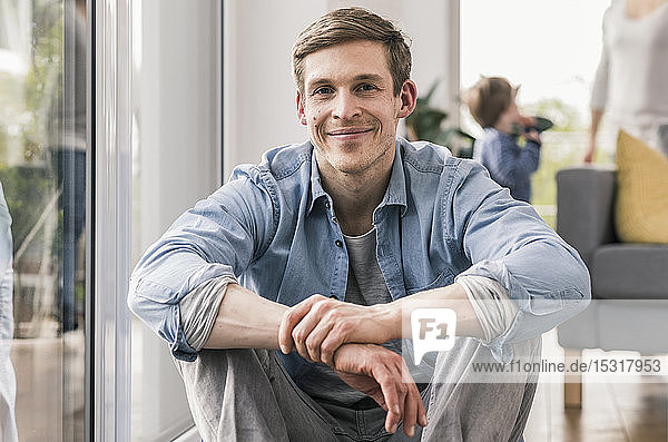 Confident man sitting on floor of his home  smiling