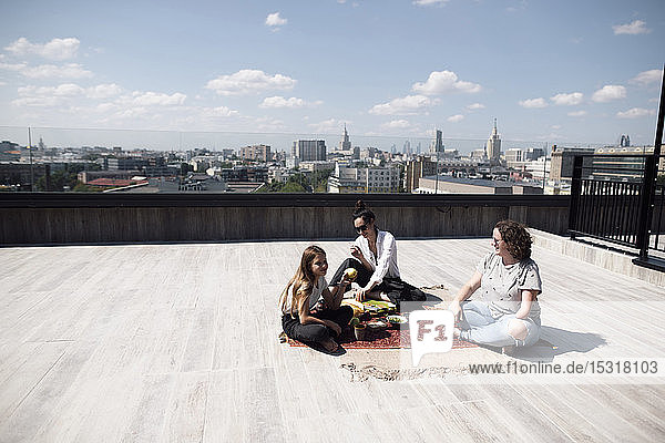 Frau mit Unterarmamputation isst mit Frau und Mädchen gesund auf dem Dach
