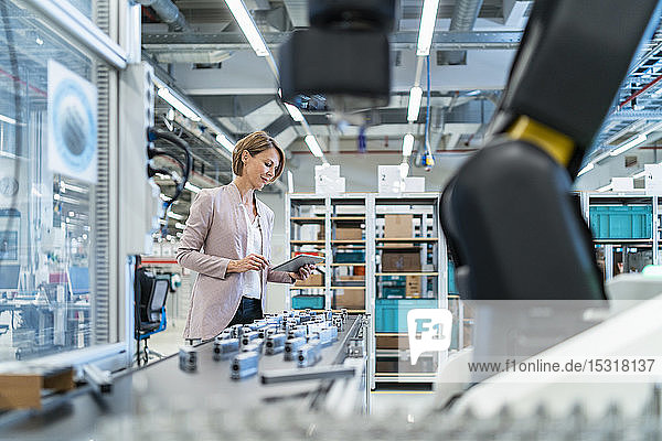 Geschäftsfrau mit Tablette in einer modernen Fabrikhalle