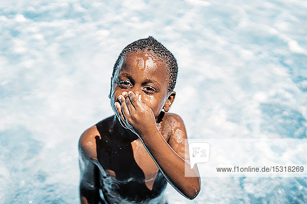 African child having fun in swimming pool  holding nose