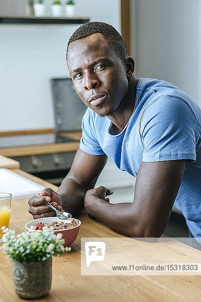 Porträt eines jungen Mannes beim Frühstück in der heimischen Küche