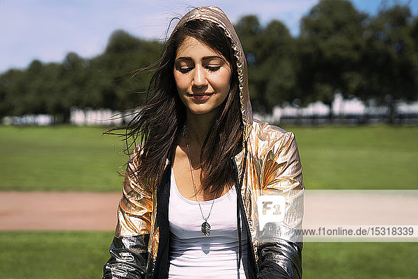 Portrait of young woman wearing shiny jacket  hood