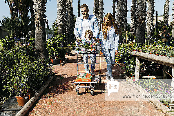 Familie kauft Pflanzen in einem Gartencenter mit der Tochter im Einkaufswagen