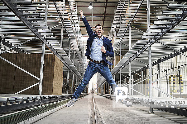 Excited businessman jumping in factory