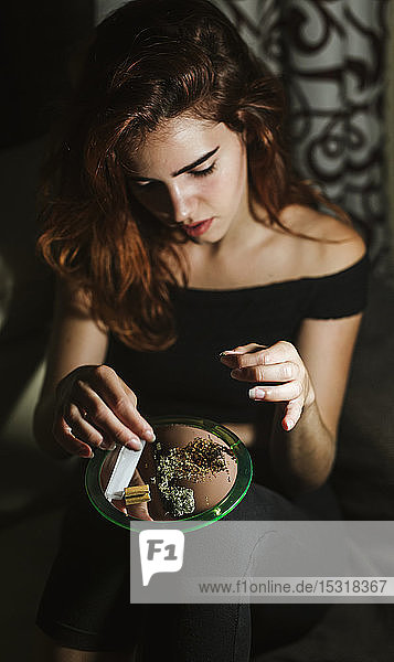 Young woman rolling a joint at home