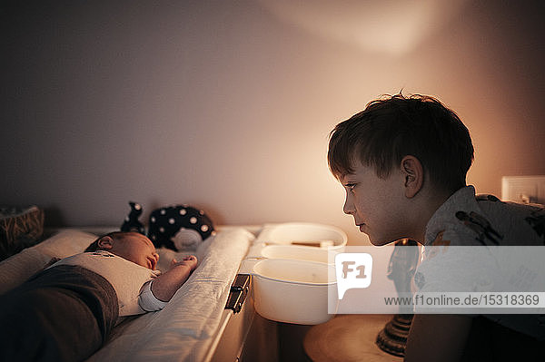 Older boy looking at the baby lying on the changing table