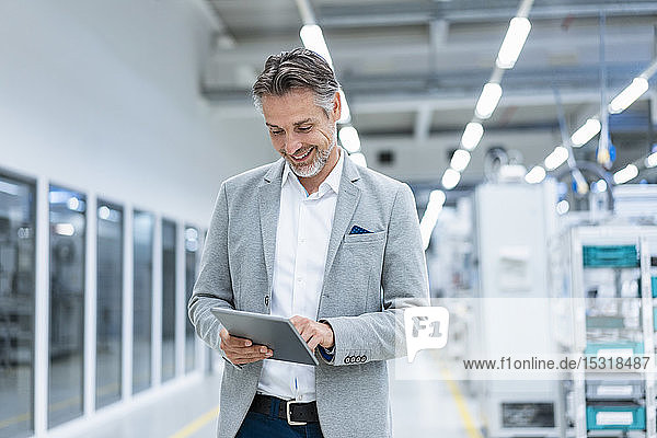 Smiling businessman using tablet in a modern factory