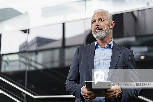 Mature businessman with tablet looking around