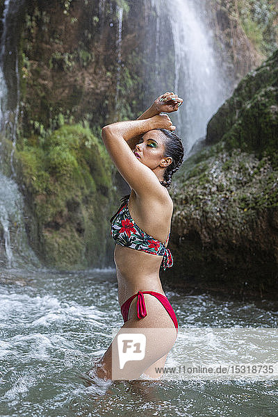 Junge Frau posiert mit verbranntem Körper im Wasserfall