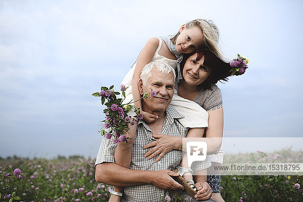 Porträt eines kleinen Mädchens und seiner Großeltern mit gepflückten Blumen in der Natur