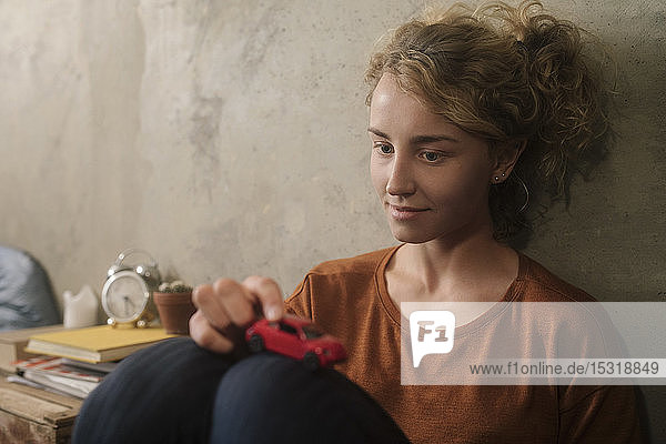 Portrait of oung woman playing with red toy car
