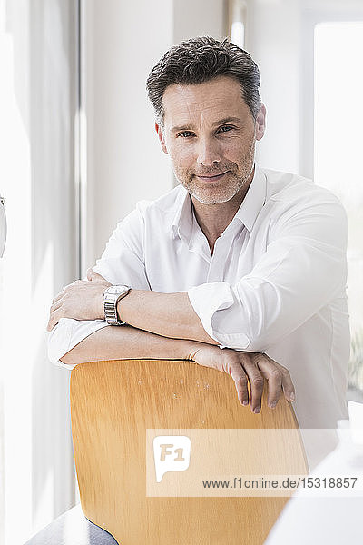 Mature man sitting on chair backwards smiling