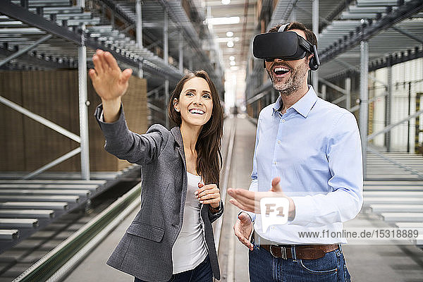 Happy businesswoman and businessman wearing VR glasses in factory