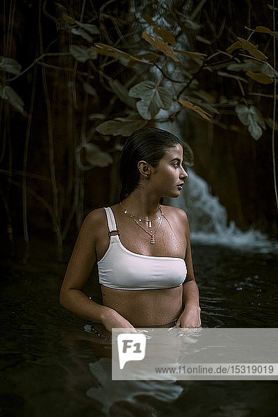 Junge Frau in einem See mit einem Wasserfall im Hintergrund