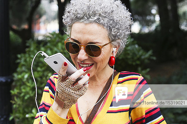Portrait of pierced mature woman using smartphone outdoors