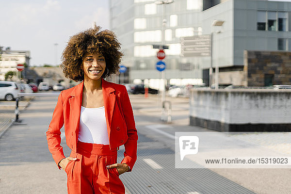 Portrait of smiling young woman wearing fashionable red pantsuit