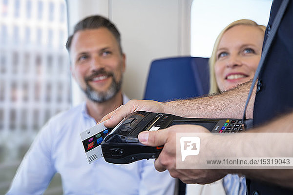 Schaffner bei der Fahrkartenkontrolle von Reisenden in einem Zug
