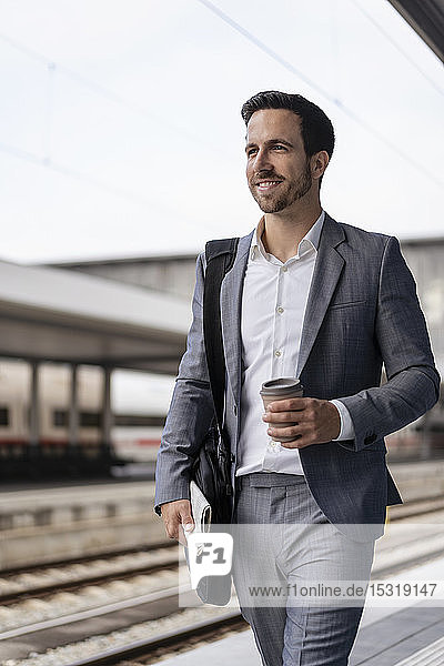 Geschäftsmann mit Kaffee zum Mitnehmen auf dem Bahnsteig