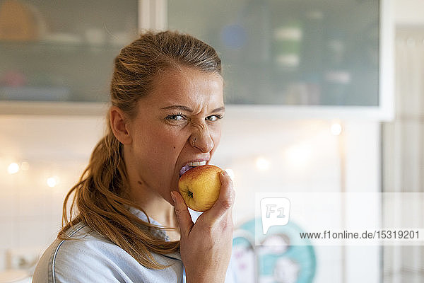 Porträt einer jungen Frau  die zu Hause einen Apfel isst
