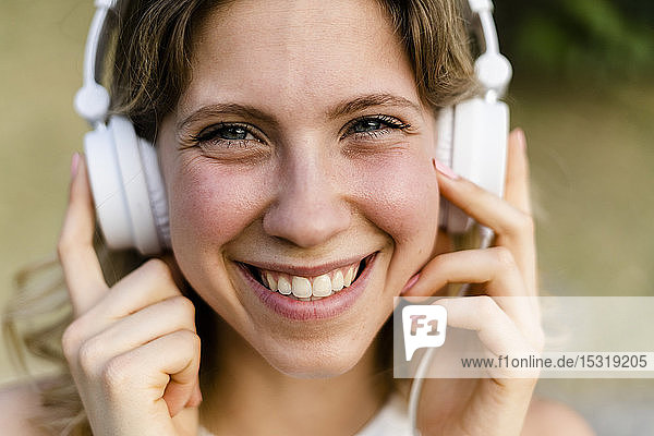 Porträt einer glücklichen jungen Frau  die mit Kopfhörern Musik hört