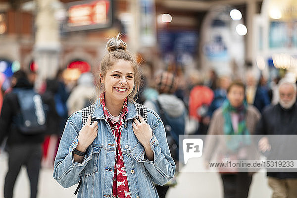 Porträt einer glücklichen jungen Frau am Bahnhof