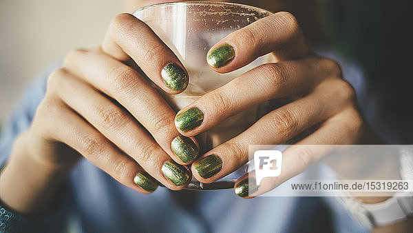 Close-up of female hands holding a glass of coffee
