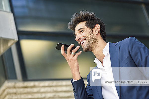 Happy businessman using cell phone outside an office building