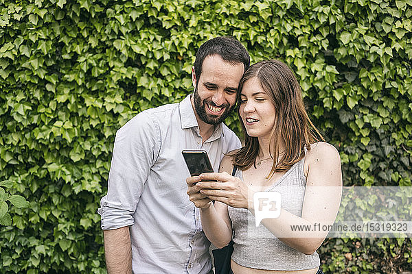 Happy young couple sharing cell phone