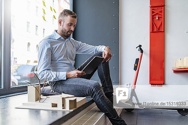 Businessman with tablet and architectural model in office