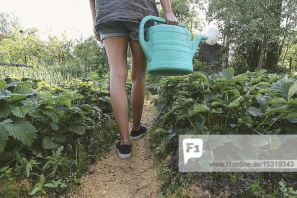 Close-up of woman with watering can walking in garden