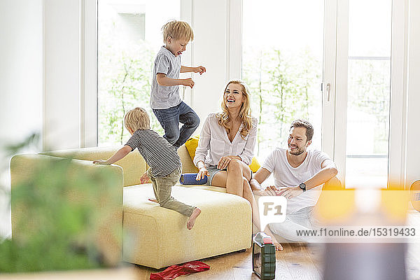 Happy family in living room of their new home with boys romping about