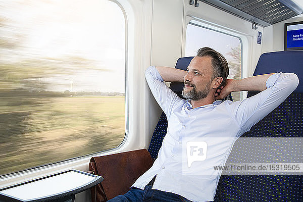 Reifer Mann sitzt im Zug und entspannt sich